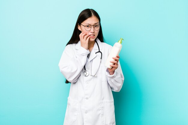 Muchacha asiática joven del dermatólogo que se muerde las uñas, nerviosa y muy ansiosa.