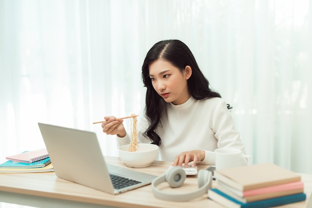 La muchacha asiática joven que se sienta en el trabajo del escritorio horas extras, disfruta de la relajación time.female trabajando.