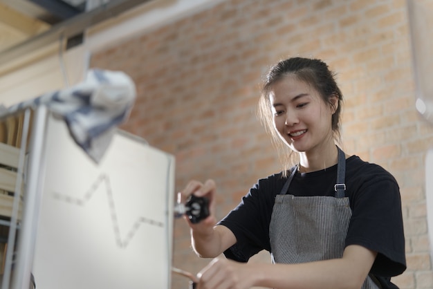 Muchacha asiática linda joven del barista que hace el café en cafetería.