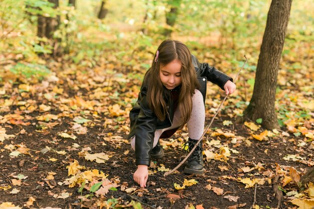 Muchacha asiática del niño que juega en el otoño en el concepto de la infancia y de la estación del paseo de la naturaleza al aire libre