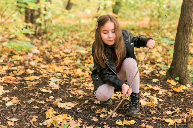 Muchacha asiática del niño que juega en el otoño en el concepto de la infancia y de la estación del paseo de la naturaleza al aire libre