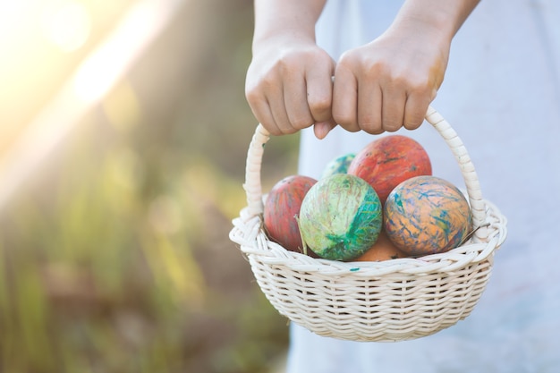 Foto muchacha asiática del niño que sostiene la cesta con los huevos de pascua coloridos