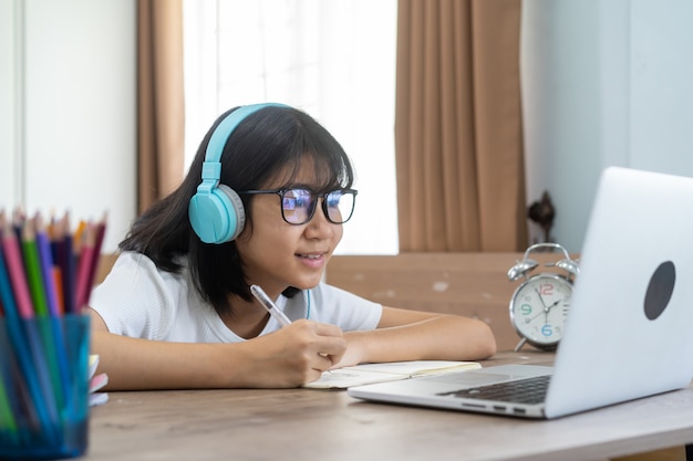 Muchacha asiática que estudia la lección en línea de la tarea en casa, concepto de idea de educación en línea de distancia social