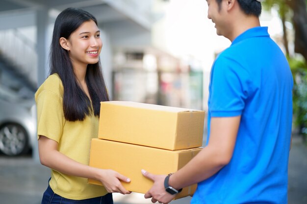 Muchacha asiática que recibe el paquete del hombre de entrega, entregando la caja del paquete. Rápido y confiable