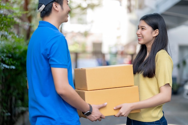 Foto muchacha asiática que recibe el paquete del hombre de entrega, entregando la caja del paquete. rápido y confiable