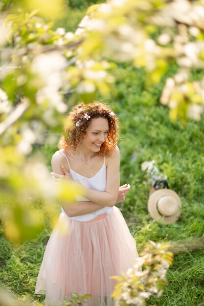 La muchacha atractiva joven camina en el parque verde de la primavera que disfruta de la naturaleza floreciente