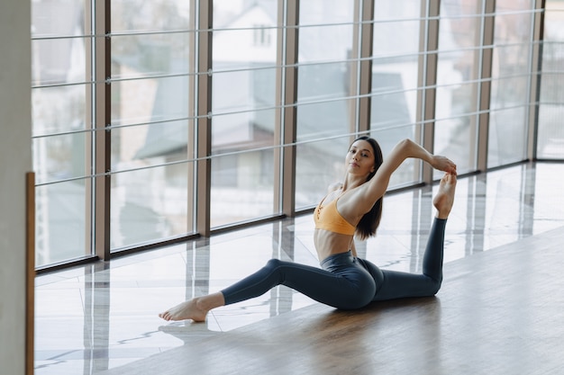 La muchacha atractiva joven que hace aptitud ejercita con yoga en el piso