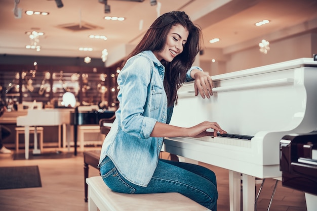 Foto la muchacha atractiva joven está tocando el piano en tienda de la música.