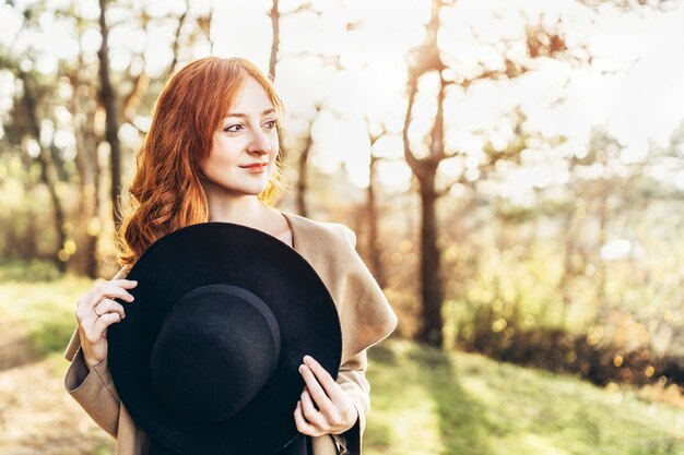 Muchacha bonita y feliz del pelo rojo que camina en el bosque