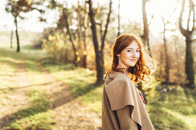 Muchacha bonita y feliz del pelo rojo que camina en el bosque