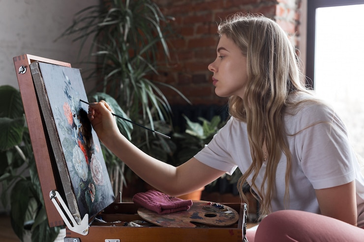 Foto muchacha bonita joven con el cepillo y la paleta que se sientan cerca de imagen del dibujo de la base