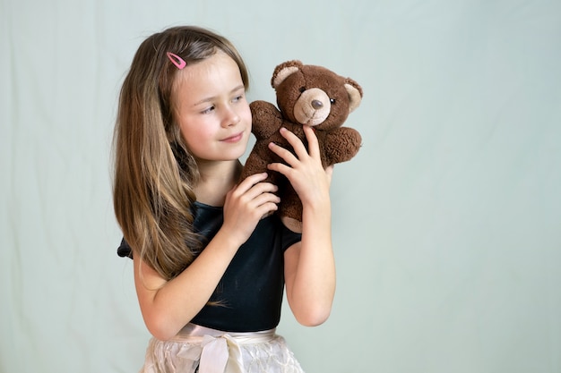 Muchacha bonita del niño que juega con su juguete del oso de peluche.