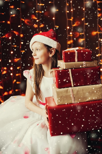 Foto muchacha bonita en el sombrero del `s de santa que prepara los regalos para la familia a la navidad.