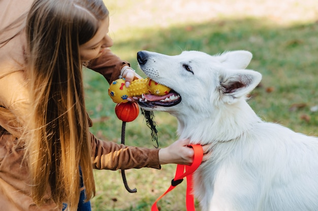 Foto la muchacha camina en el parque del otoño con el perro de pastor suizo blanco joven