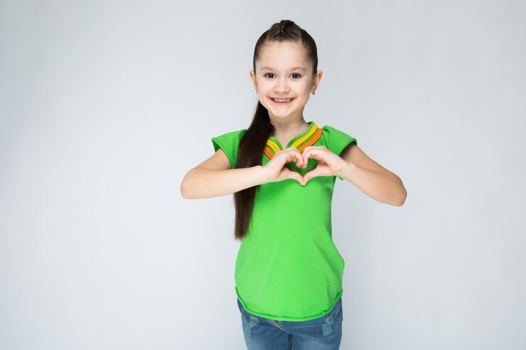 Muchacha en camiseta verde y tejanos en fondo gris.