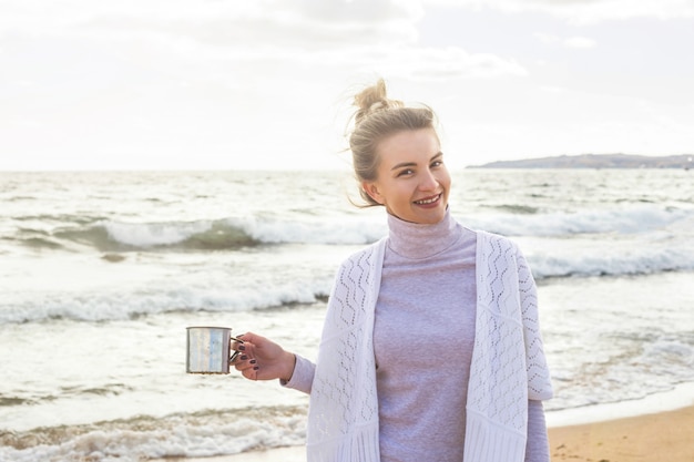 La muchacha caucásica disfruta de la naturaleza y viaja al mar en un día ventoso de otoño.