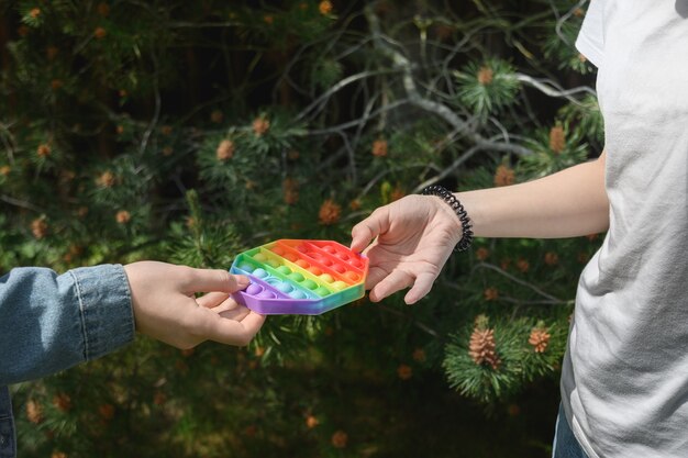La muchacha da el estallido anti colorido de la tensión del silicón popular él juguete de la forma del hexágono