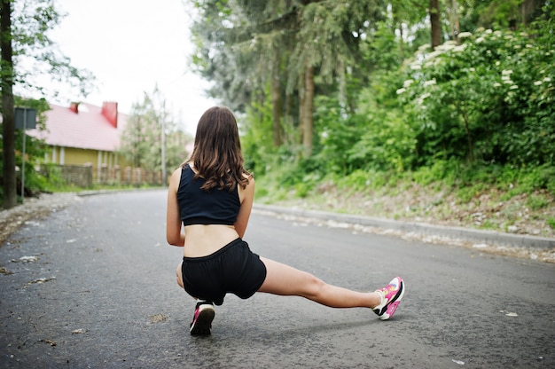 Muchacha del deporte en la ropa deportiva que ejercita en un parque verde y que entrena en la naturaleza.