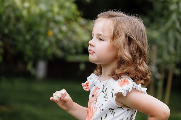 Muchacha divertida del niño que come el bocadillo al aire libre.