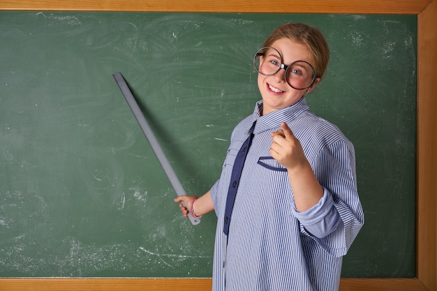 Muchacha divertida del niño en el traje del profesor de escuela