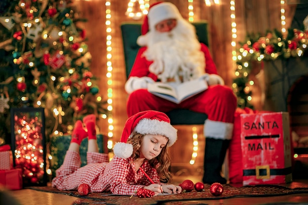 Muchacha divertida en el sombrero de Santa escribe carta a Santa