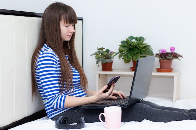 Muchacha embarazada con una computadora portátil en la cama.