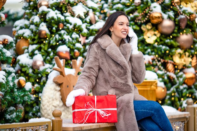 Muchacha feliz cerca de la rama de abeto en la nieve por año nuevo.