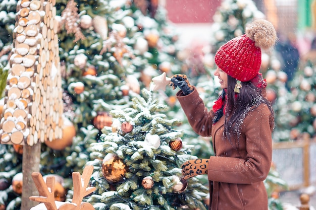 Muchacha feliz cerca de la rama de abeto en la nieve por año nuevo.