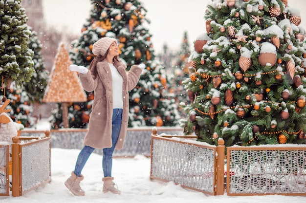 Muchacha feliz cerca de la rama de abeto en la nieve por año nuevo.