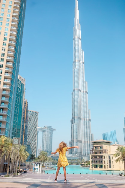 Muchacha feliz que camina en Dubai con el rascacielos de Burj Khalifa en el fondo.