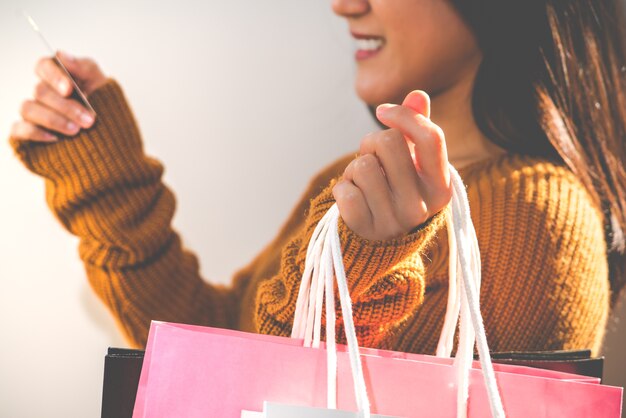 Muchacha feliz que sostiene el bolso de compras y la tarjeta de crédito coloridos para el regalo del Año Nuevo de la familia