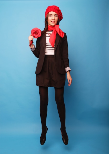 Foto muchacha hermosa en una boina roja. estilo francés. sobre fondo azul.