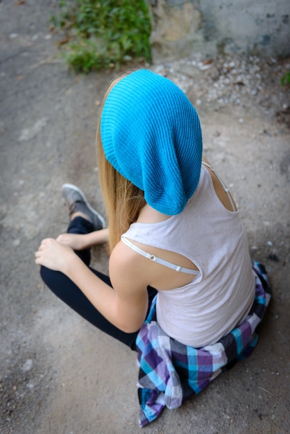 La muchacha hermosa en un casquillo azul en paseo