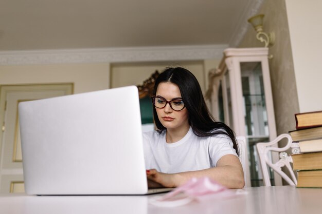 Muchacha hermosa joven con una computadora portátil en casa