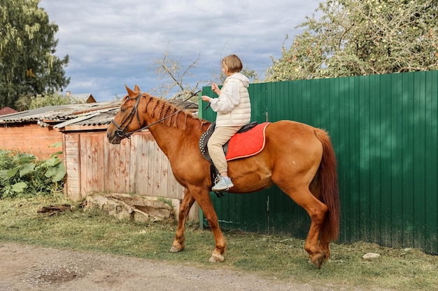 La muchacha hermosa joven monta su caballo a los caminos del país en otoño