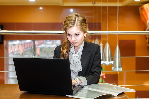 Muchacha hermosa joven que trabaja en una computadora portátil