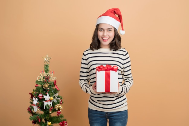 Muchacha hermosa de la Navidad en el sombrero de santa con las cajas en fondo del otoño.