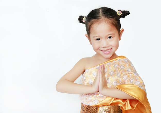 Muchacha hermosa del niño asiático en el vestido tailandés tradicional que ruega en el fondo blanco.