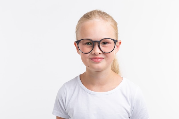 Muchacha hermosa del niño con gafas aisladas en blanco.