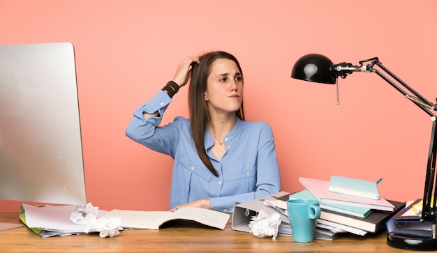 Foto muchacha joven del estudiante que tiene dudas mientras que rasguña la cabeza