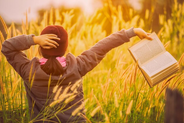 Muchacha y libro asiáticos en un invierno de la pradera.