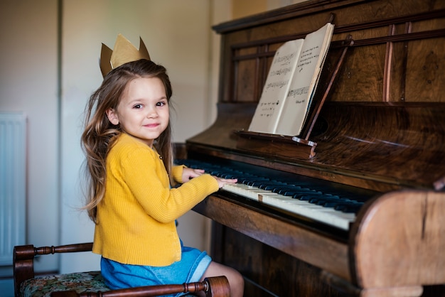 Muchacha linda adorable que juega concepto del piano