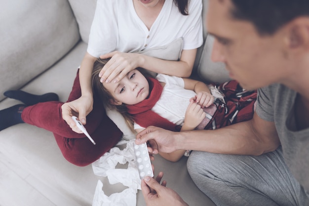 La muchacha miente en el regazo de su madre. Mujer tiene termómetro.