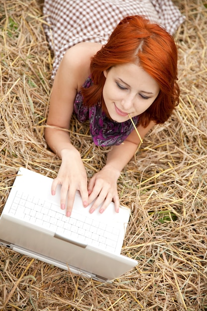 Muchacha de la moda joven con el cuaderno que miente en el campo