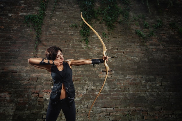 Foto muchacha morena atlética en el tiroteo negro del arco.