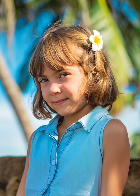 Muchacha del niño en el fondo de palmeras y océano. enfoque selectivo.