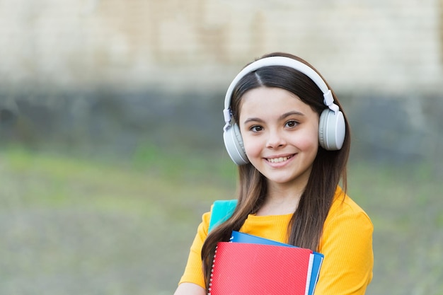 Muchacha del niño moderno con auriculares de regreso a la escuela mantenga el libro de texto, concepto de enfoque moderno.