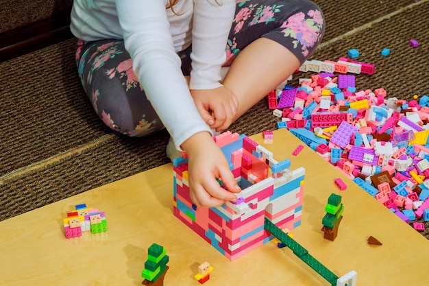 Muchacha del niño que se divierte y estructura de bloques de construcción de plástico brillante.