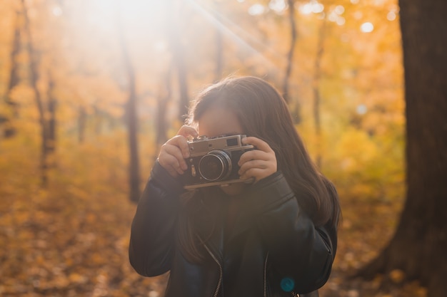 Muchacha del niño que usa una cámara pasada de moda en otoño la temporada de otoño y el ocio del fotógrafo de la naturaleza