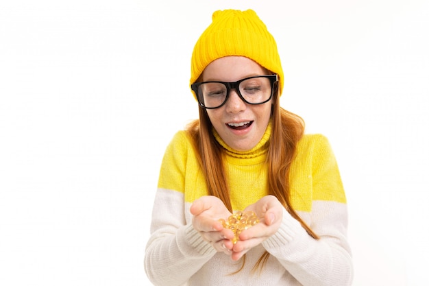 La muchacha pelirroja europea sonriente en vidrios sostiene las lentes en blanco